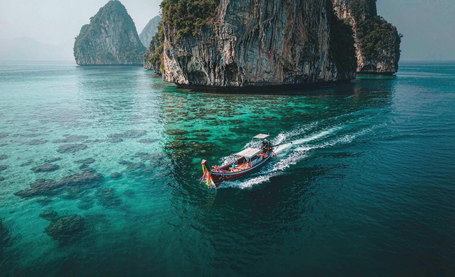 A longtail boat crossing turquoise water in the Andaman Sea